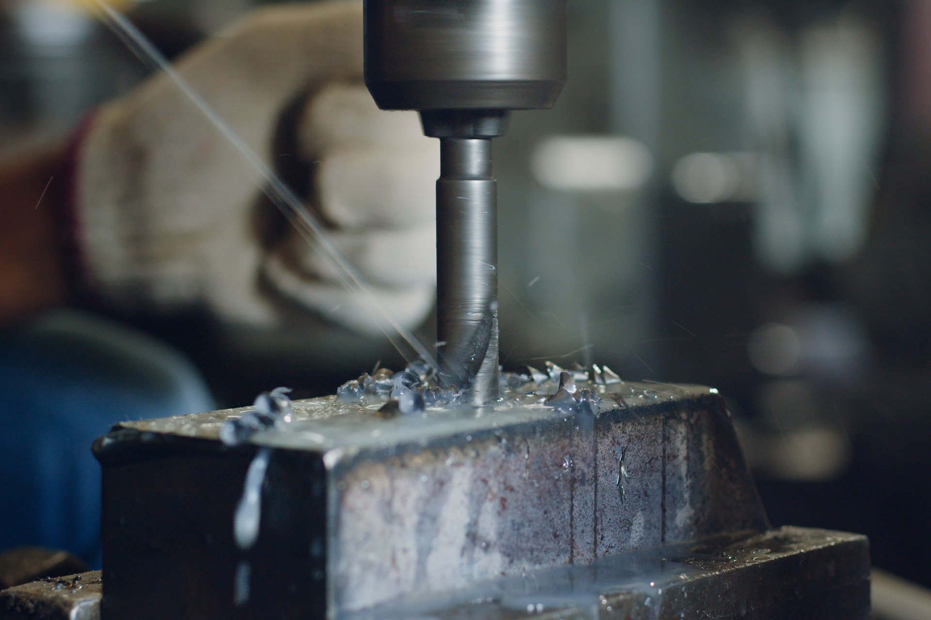 Technician worker using drilling machine for metalworking in workshop factory