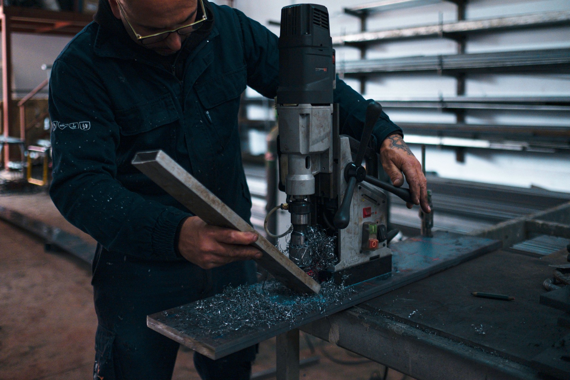 Metal worker drilling a metal beam with a magnetic drill press